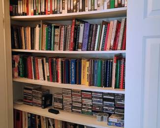 Top shelf is VHS, next 2 shelves are cookbooks, cassettes and CDs on 4th shelf