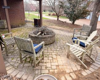 Stone fire pit with Adirondack chairs and patio furniture on paver patio