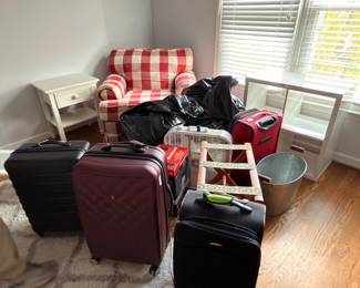 Assorted luggage and suitcases with checkered armchair