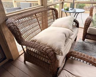 Wicker patio furniture set with glass-top table on screened porch