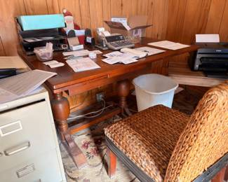 Wooden desk, metal file cabinet, wicker chair, and office supplies
