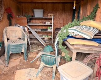 Stacked patio chairs, cushions, Christmas decor, and seasonal items