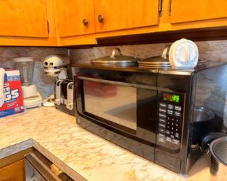 Microwave, pots, pans, and kitchen cookware on counter
