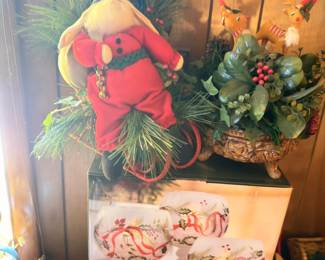 Christmas decor, stuffed Santa figure, holly greenery, gift bags