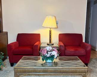 Red upholstered armchairs flanking a glass-top rattan coffee table with a decorative lattice design