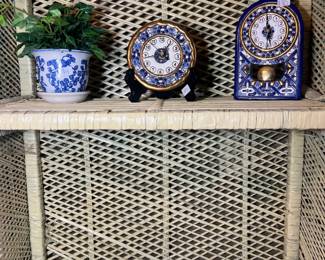 A classic cream-painted wicker shelf featuring an elegant arched top and intricate latticework, shown with decorative blue and white porcelain and collectible mantle clocks