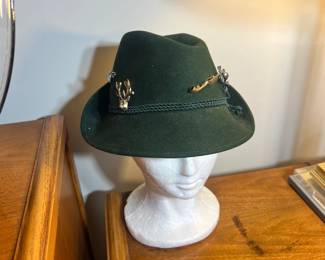 Tyrolean Alpine Hat: Traditional green felt with decorative pins including a stag head and pipe