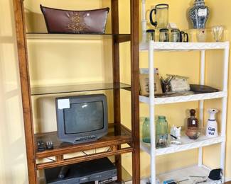 A tall wood-frame glass etagere housing a Sanyo CRT TV and VCR, barware, and antique glass jars