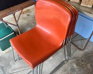 Four vintage orange molded shell chairs with chrome sled bases, perfect for a retro dining or office setup