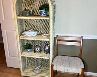 A classic cream-painted wicker shelf featuring an elegant arched top and intricate latticework, shown with decorative blue and white porcelain and collectible mantle clocks