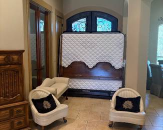 King wooden bed frame/ Ashely furniture king mattress/ white end of bed bench/ two mid-century wheeled white chairs.