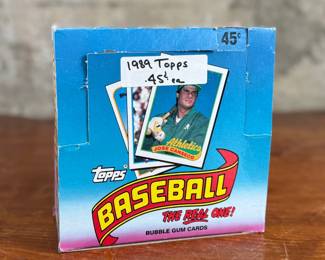 This lot features a collectible box of sealed 1989 Topps Major League Baseball trading card packs. The box contains many packs, each featuring 15 baseball cards and one stick of bubble gum. These packs were part of a “Spring Fever Baseball” promotion offering a chance to win a trip to 1990 Spring Training.