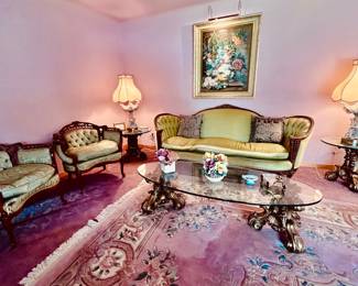 Living area with Victorian Vintage Sofa, Wing back chirs , Beautiful glass tables gold  sculpture legs elegant pic on wall 