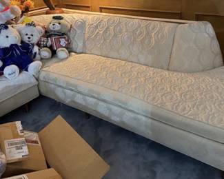 Stunning Mid-Century Modern/ MCM low-profile sectional sofa. Features a timeless vintage silhouette with a classic cream/off-white textured brocade upholstery showcasing an elegant geometric pattern. Designed with clean modernist lines, a comfortable deep-seated configuration, and beautifully integrated padded armrests. Top of sofa features a walnut insert perfect for a lamp, drinks or objet d'art. A rare, high-quality vintage statement seating piece perfect for any mid-century modern or retro living room setup!