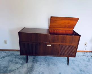 Stunning 1960s Mid-Century Modern West German stereo console cabinet by Telefunken. Features gorgeous wood-slat vertical speaker grilles, clean Scandinavian design lines, and iconic tapered legs. The wooden cabinet body is in exceptional vintage condition with beautiful grain patterns and minimal wear. The top lids lift up to access the integrated vintage stereo receiver, and the center features a classic drop-down media storage bay. The original turntable is intact but currently non-functional—making this a perfect aesthetic credenza, a Bluetooth conversion project, or a restoration piece for vintage audio enthusiasts!