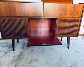 Stunning 1960s Mid-Century Modern West German stereo console cabinet by Telefunken. Features gorgeous wood-slat vertical speaker grilles, clean Scandinavian design lines, and iconic tapered legs. The wooden cabinet body is in exceptional vintage condition with beautiful grain patterns and minimal wear. The top lids lift up to access the integrated vintage stereo receiver, and the center features a classic drop-down media storage bay. The original turntable is intact but currently non-functional—making this a perfect aesthetic credenza, a Bluetooth conversion project, or a restoration piece for vintage audio enthusiasts!