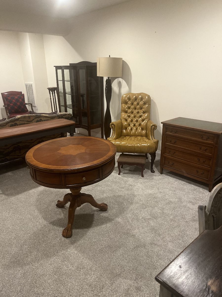 Mahogany round antique tables, vintage curio cabinet, tuft leather armchair, wooden antique furniture.