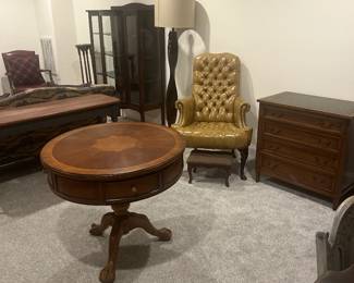 Mahogany round antique tables, vintage curio cabinet, tuft leather armchair, wooden antique furniture.