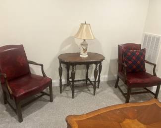 Leather arm chairs, wooden Edwardian side table, lamps.
