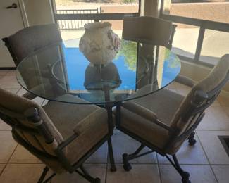 48 inch glass and metal dinette table with four rolling upholstered chairs