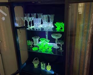 Uranium (some Fenton!) and Manganese glass fill this cabinet.  Upper left  shelf is Cambridge  Rose Point crystal.  We are proud to offer the Ice Tea glasses,  water goblets, tall champagne/sherbert glasses and the wine glasses, as well as a cream and sugar dish.