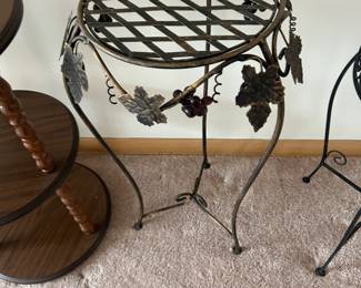 Unique metal plant stand or accent table featuring an open lattice top and detailed grapevine design. The piece is adorned with sculpted leaves, curling tendrils, and decorative grape clusters, giving it a charming Tuscan or vineyard-inspired look.  The airy metal construction and curved legs make it both sturdy and visually light—perfect for displaying plants, décor, or as a small accent table in a living room, sunroom, or patio-style setting.  A great companion piece to other grapevine or wrought iron décor.  Condition:  Good condition with light wear and patina consistent with age. Structurally solid.  Priced at $45