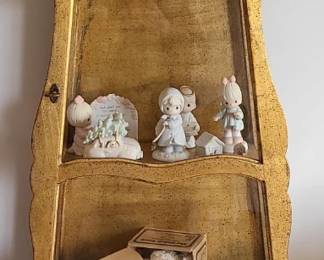 A tall, narrow vintage gold display cabinet with an ornate, antique‑style design. The frame has a curved, decorative top and sides, giving it an elegant silhouette. The upper section features two glass panels that showcase the interior shelves, perfect for displaying collectibles, glassware, or small décor. The lower portion has a solid wood door for hidden storage. The gold finish shows natural patina and age, which adds character and makes it a charming statement piece for traditional, Hollywood Regency, or eclectic interiors.  Priced at $150