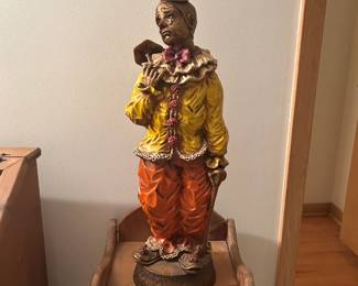 Eye-catching vintage clown figurine featuring a hand-painted design with rich colors and expressive detail. This piece showcases a classic sad clown motif, dressed in a yellow ruffled shirt, orange trousers, and a small hat, holding a prop that adds character and charm.  Crafted with textured detailing and a carved-look finish, this decorative statue has a nostalgic, old-world feel—perfect for collectors of clown memorabilia, circus-themed décor, or vintage figurines. A unique conversation piece for display on shelves, cabinets, or accent tables.  Priced at $40