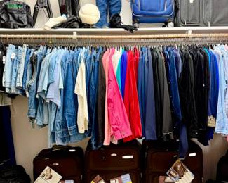 Women's closet with luggage and lots of shoes on the side.