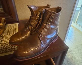 Pair of brown leather lace-up boots stacked on top of another pair on a small wooden stand.