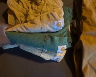 Stack of folded clothing in yellow and blue tones resting on top of a dark bag or suitcase.