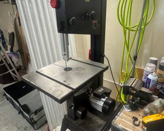 Side view of a benchtop band saw with adjustable table in the garage workshop.