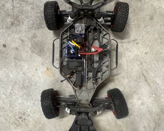 Remote-controlled off-road car chassis with black frame and four large wheels.