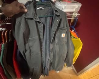 Group of jackets and coats hanging on hangers, including a grey Carhartt hooded jacket.