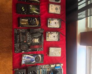 Red wall-mounted display board filled with various computer components and electronics, including several video graphics cards.