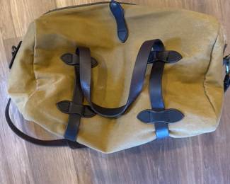 Top view of tan canvas duffel bag with black straps and carrying handles.