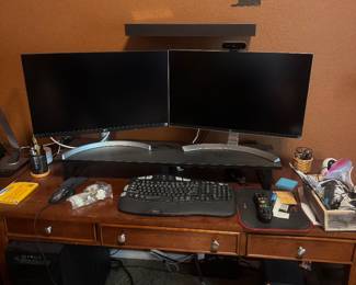 Computer workstation with two monitors on a wooden desk, along with keyboard, mouse, and accessories.