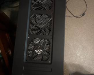 Top view of a black computer tower featuring mesh ventilation and cooling fans.