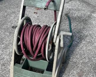 A Suncast brand portable hose reel cart designed for easy transport around the yard. • Includes: Heavy-duty red rubber garden hose and a multi-pattern spray nozzle. • Features: Crank handle for easy winding and a mobile 2-wheel design to prevent heavy lifting.