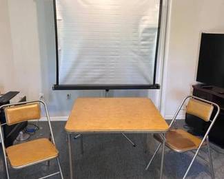 Step back into the 1960s with this classic "Mad Men" era game night set. Perfect for a basement bar, man cave, or retro sunroom, this lot includes: Four (4) Folding Armchairs: Sturdy mid-century construction featuring padded backrests and seats upholstered in a period-correct tan/beige vinyl. All four chairs are in good, functional condition. Square Folding Card Table: A matching portable table with a durable vinyl top, perfect for poker night, puzzles, or a vintage-style office overflow desk. Design & Portability: Both the chairs and table feature an easy-fold design for quick storage, though the style is handsome enough to leave out as a permanent fixture. Condition: In good vintage condition. Shows light, age-appropriate character wear on the metal frames and vinyl, consistent with a set that has hosted decades of cards and conversation.