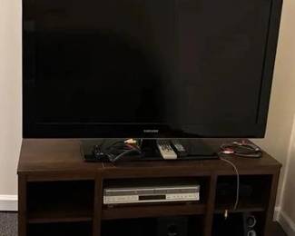 46 inch Samsung TV with wood like particleboard TV stand 45 inches long 16 inches wide 21 inches tall soToshiba DVD and VHS player along with speaker