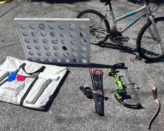 GoSports Giant Connect 4 Game: Includes the white game board, a matching tan carrying case, and red and blue playing discs. Roadmaster MT-Fury Mountain Bike: A silver 15-speed mountain bike with 24-inch wheels and a Shimano drivetrain. Archery Equipment: Includes a neon green Bear Archery youth compound bow, a traditional wooden recurve bow, and a quiver with multiple arrows.