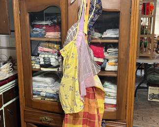 Nice cabinet filled with kitchen towels, runners & table cloths