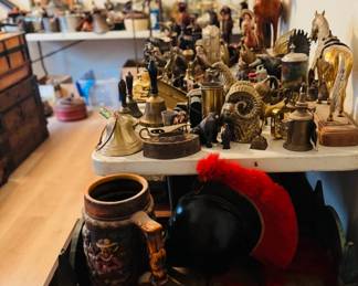 Close-up of antique and vintage smalls table featuring brass bells, animal figurines, horse statues, primitive metalware, Western decor, and unusual collectible display pieces. Strong mix of rustic, farmhouse, and one-of-a-kind antique finds for collectors, decorators, and resellers.