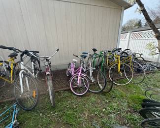 Outdoor row of vintage and used bicycles in multiple styles and colors, including road bikes, cruisers, and kids’ bikes, plus extra wheels and bike parts. Great selection for riders, restorers, parts buyers, and pickers hunting for project bikes and outdoor finds.