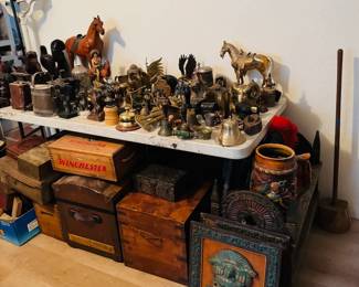 Antique and collectible table loaded with brass bells, figurines, horse statues, primitive metalware, carved pieces, storage boxes, and vintage decorative smalls. Great assortment of rustic, Western, and unusual display items for antique buyers, collectors, and resellers.