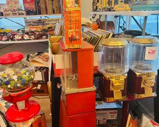 Vintage vending and nostalgia display featuring gumball machines, retro radios, jukebox-style pieces, records, toy models, and collectible advertising decor. Fun mix of coin-op style items, music memorabilia, and colorful display pieces for collectors, decorators, and resellers.