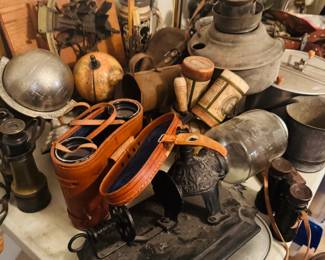 Antique optics and industrial collectible table featuring vintage binoculars, opera glasses, old lanterns, metalware, primitive tools, globes, and unusual decorative smalls. Strong mix of rustic, scientific, and one-of-a-kind picker pieces for antique buyers, collectors, and resellers.