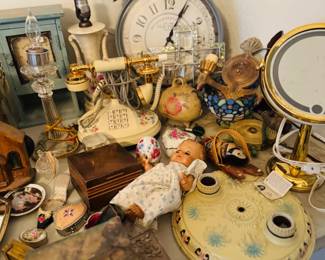 Vintage vanity and decor table featuring an old-style telephone, clocks, lamps, mirrors, trinket boxes, doll, and mixed shabby chic and nostalgic collectibles. Nice assortment of decorative smalls, boudoir pieces, and vintage household accents for collectors, decorators, and resellers.