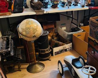 Antique and vintage vignette featuring a globe bar stand, cast iron typewriter, nautical ship models, old grinder, industrial pieces, pedal car, trunks, and primitive decor. Great mix of maritime, industrial, and unusual collectible pieces for antique buyers, decorators, and pickers.